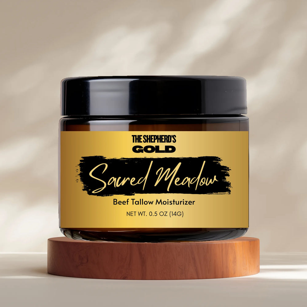 Jar of 'The Shepherd's Gold Sacred Meadow' beef tallow moisturizer on a wooden stand with a neutral background.